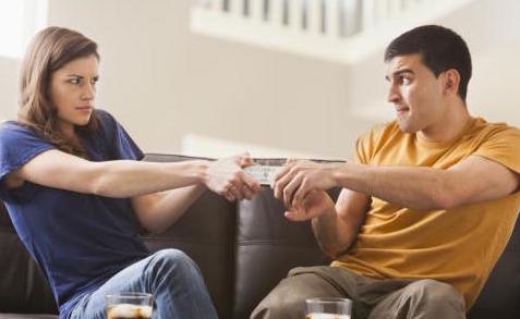 Couple arguing over remote on sofa